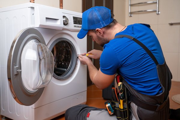 Appliance technician repairing a front-load washer.