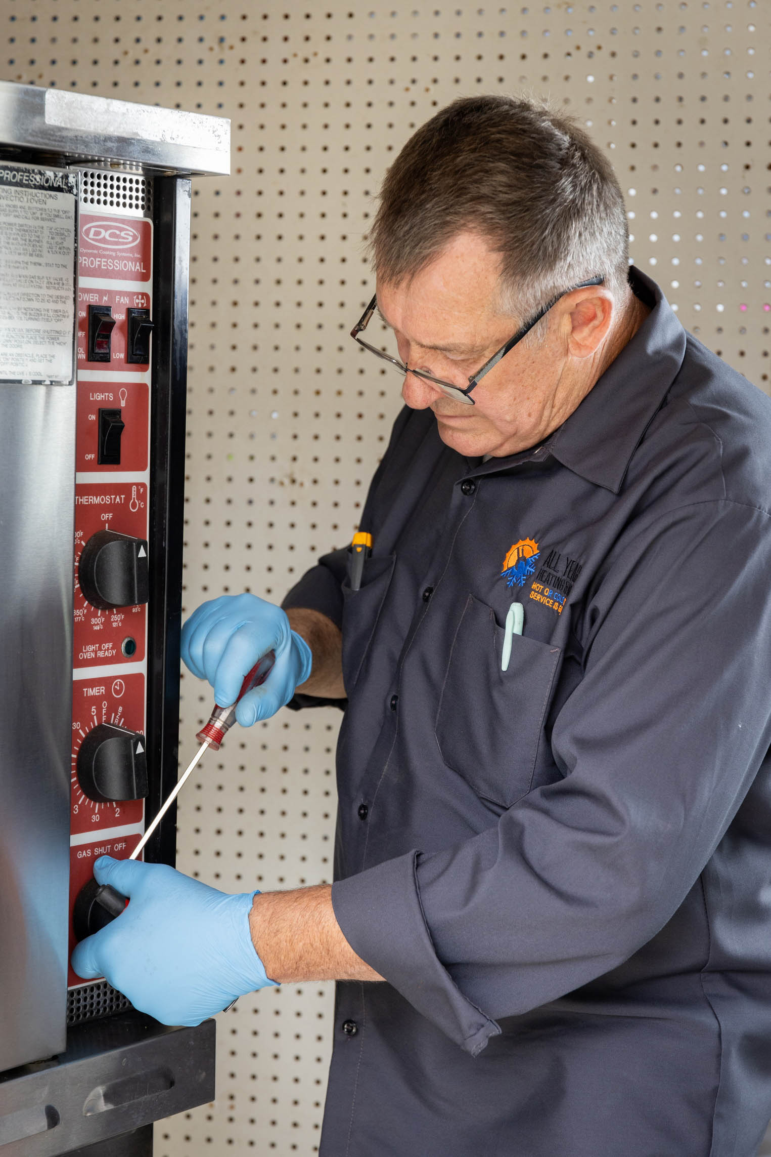 All Year technician repairing the control panel of a high-end stainless steel range